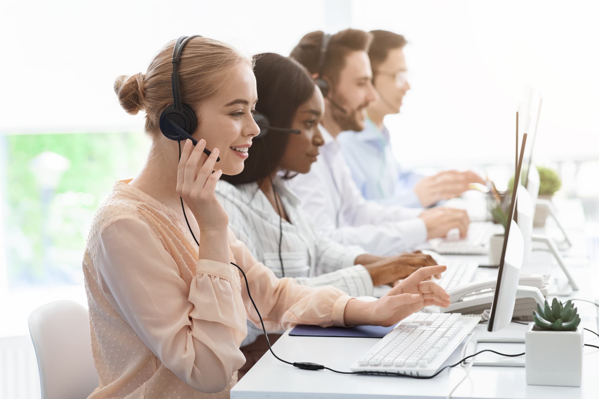 A row of contact centre advisors on headsets handling customer calls in a bright open-plan office
