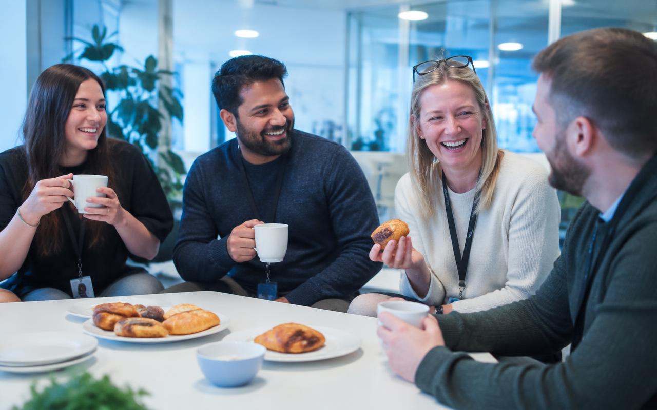 Colleagues laughing together over coffee and pastries during a team social at Telappliant
